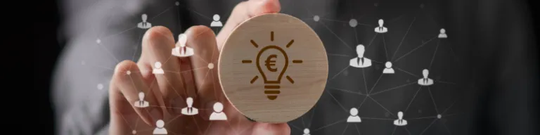 Hand holding a wooden disc with a euro symbol inside a lightbulb, over a network of connected user icons.