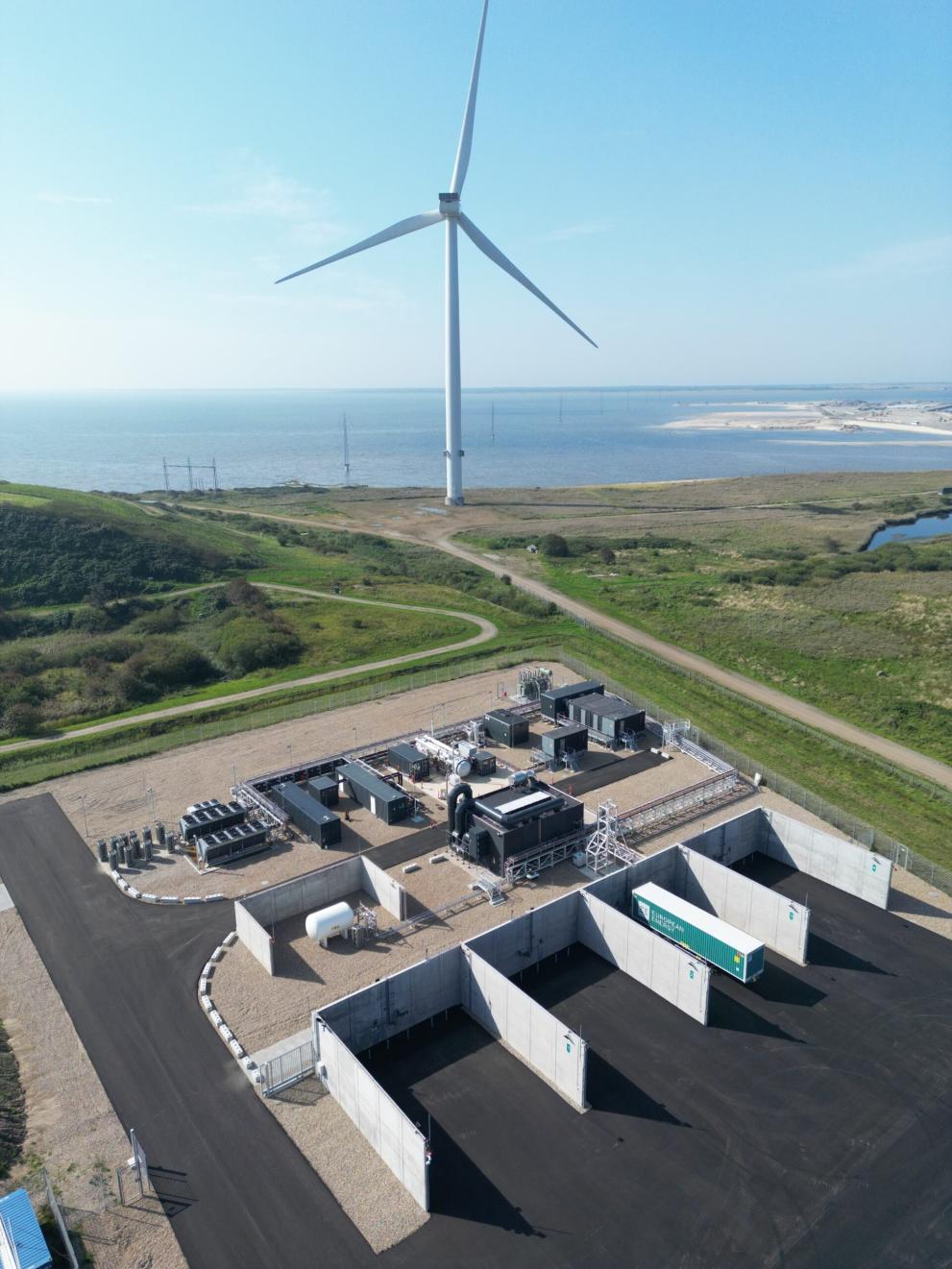 Aerial view of the Måde Power-to-X facility near the coast, featuring a wind turbine and industrial infrastructure supporting the FiBrane project’s seawater-to-UPW conversion for offshore green hydrogen production.